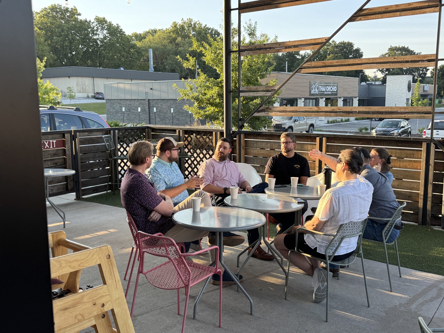 Business owners talking around tables on a coffee shop patio at sunrise